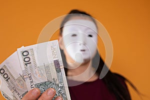 An anonymous woman stands and pulls her hand in with paper banknotes with the face value of one hundred Polish zlotys