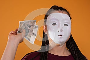 An anonymous woman stands and pulls her hand in with paper banknotes with the face value of one hundred Polish zlotys