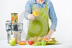 Anonymous woman wearing an apron, offering glass of freshly pressed juice, healthy lifestyle concept