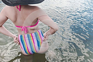 An anonymous woman wearing a fashionable high waist bikini in almost waist deep water. Vacation getaway and summer fashion theme