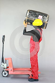 Anonymous worker lifting  heavy package. Profile view.