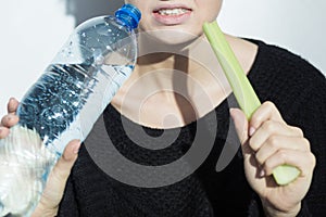 Anorexic girl holding a leek and a bottle of water