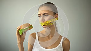 Anorexic girl ties mouth with tape-line, fights with temptation to eat burger
