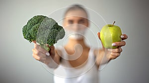 Anorexic model with taped mouth holding vegetables, concept of excessive fasting