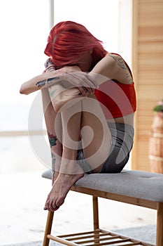 Anorexic woman hugging her knees while feeling awful