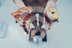 Anorexic Woman with Pizza and Apple on Weigher. photo