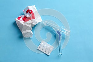 Anoscope, suppositories and toilet paper with blood on blue background, flat lay. Hemorrhoid treatment