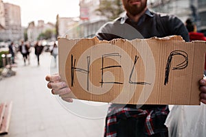 Another picture of cardboard which says help. It is hold by a jobless man. He is also a homeless man. He is looking for