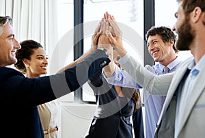 Another successful deal for the dream team. a group of excited businesspeople giving each other a high five.