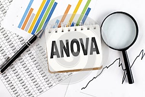 ANOVA text on notebook on the graph background with pen and magnifier