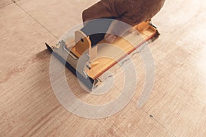 An anoynymous carpenter uses sandpaper attached to a sanding block or manual hand sander to polish the surface of a sheet