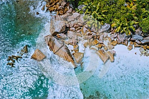Anse Cocos beach tropical island La Digue Seychelles. Drone aerial view of foam ocean waves rolling towards the rocky