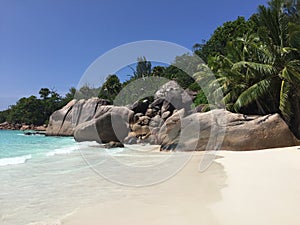 Anse Lazio white sand beach with boulders,  turquoise water and palm trees