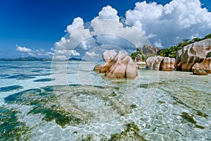 Anse Source d`Argent in low tide - Paradise tropical beach with shallow blue lagoon, granite boulders and white clouds
