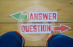 Answer or Question opposite direction signs with sneakers on wooden