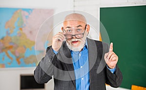 Answer and question. senior man teacher at blackboard. bearded tutor in glasses near geography map. back to school
