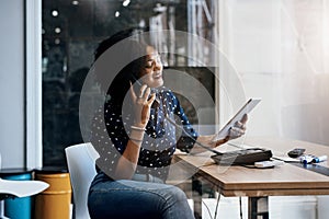 She always answers when opportunity calls. a young female designer making a phone call while holding a digital tablet at