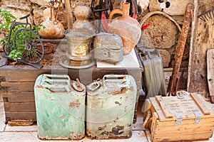 A group of old canisters, cylinders and some other tings stand on shelves in a wooden shed