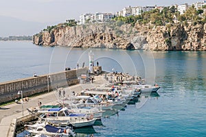 Antalya, Turkey - November 15, 2022: Small fishing boats at the harbor with a lighthouse