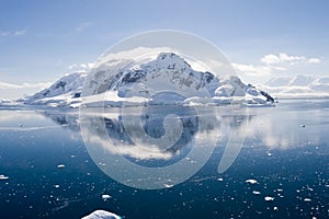 Antarctic ice-covered mountain reflected in water photo