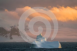 Antarctic Iceberg nature landscape during midnight sun sunset sunrise in the horizon. Early morning summer alpenglow