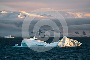 Antarctic Iceberg nature landscape during midnight sun sunset sunrise in the horizon. Early morning summer alpenglow