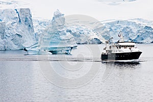 Antarctic iceberg, beautiful shaped iceberg with research ship in front