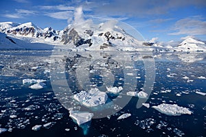 Antarctic landscape with snow covered mountains, glacier, dark blue sea with ice floes and reflections, Paradise Bay