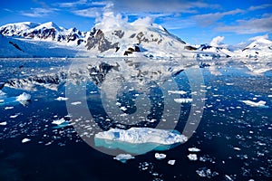 Antarctic landscape with snow on mountains reflecting in blue water, ice flows, Lemaire Channel near Paradise Bay, Antarctica