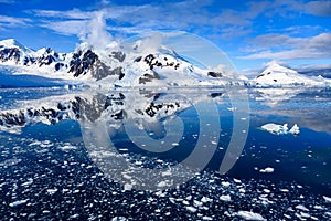 Antarctic landscape, snow on mountains reflecting in blue water, ice flows, Lemaire Channel near Paradise Bay, Antarctica