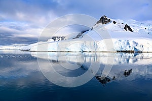 Antarctic ndscape with mountains reflecting in dark blue water of Lemaire Channel near Paradise Bay, Antarctica