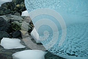 Antarctica unique shiny clear blue iceberg art texture  on rocky beach