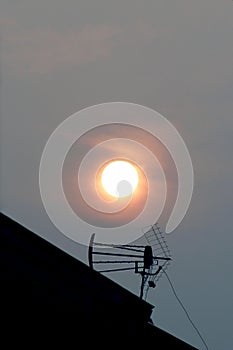 Antenna on the roof of a house with the sun