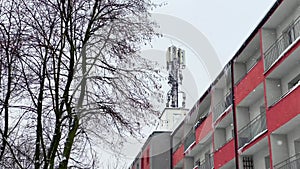 Antennas for cellular transmitters on roof of residential building. Radio emission. FaÃ§ade of house with windows. Mobile