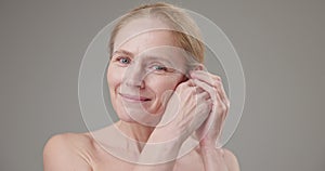 Anti age, Beauty, health and dry skin care concept - beautiful middle-aged mature Caucasian woman in her 50s touching