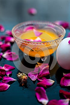 Anti-aging face pack i.e.  Milk and egg face pack in a glass bowl on shiny black surface with some rose petals