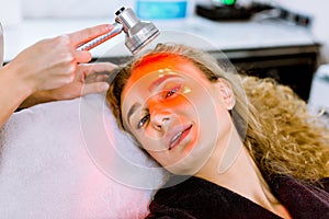 Anti-aging procedures. Skin care concept. Pretty blond woman receiving facial beauty treatment at modern cosmetic clinic