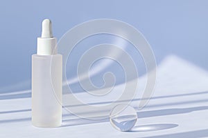 Anti aging serum with collagen and peptides on blue surface with shadows. Hyaluronic acid oil mockup. Sunlight and