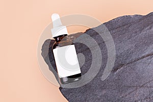 Anti aging serum with collagen and peptides in dark glass bottle with dropper on the stone isolated on beige background. Skincare