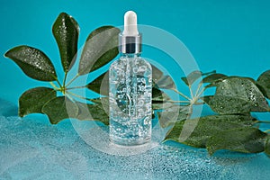 Anti aging serum with collagen and peptides in glass bottle with dropper on a wet blue background