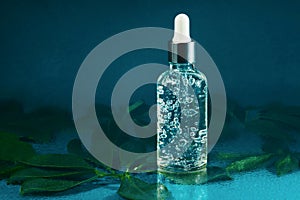 Anti aging serum with collagen and peptides in glass bottle with dropper on a wet blue background