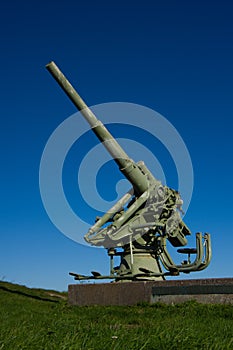 Anti-aircraft gun on a granite pedestal, on the background of blue sky