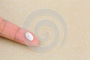 Anti anxiety white pill medicine on finger with blurred yellow b