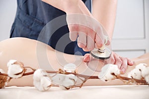 Anti-cellulite thigh massage using vacuum jars cans banks. Man putting physiological therapist`s vacuum can on female