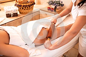 Anti-cellulite treatment with a help of a wooden roller photo