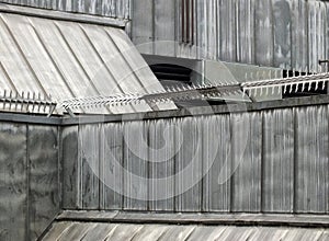 Anti climb security rollers with barbed spikes on the walls and roof of a high security building with grey sloping surfaces