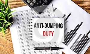 ANTI-DUMPING DUTY text on notebook on chart with calculator and pen