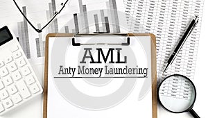 Anti-money laundering AML text on clipboard on light background with charts paper