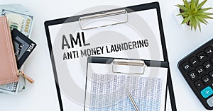 Anti-money laundering AML text on a clipboard on light background with charts paper