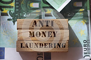 Anti Money laundering concept, words on wooden blocks on 100 euro banknotes